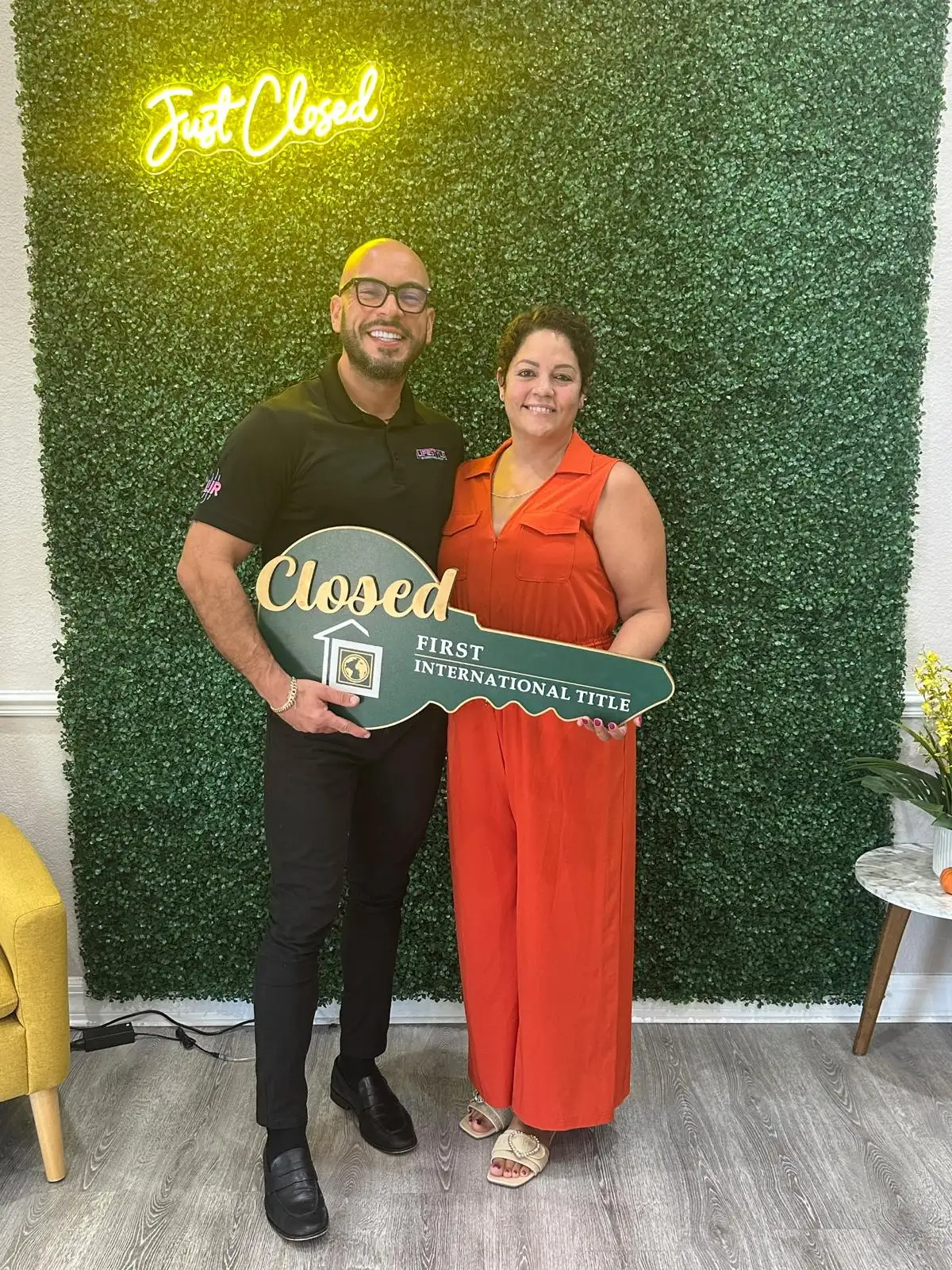 Jose Alberto Gomez and a client holding a giant "Closed" key under a "Just Closed" neon sign